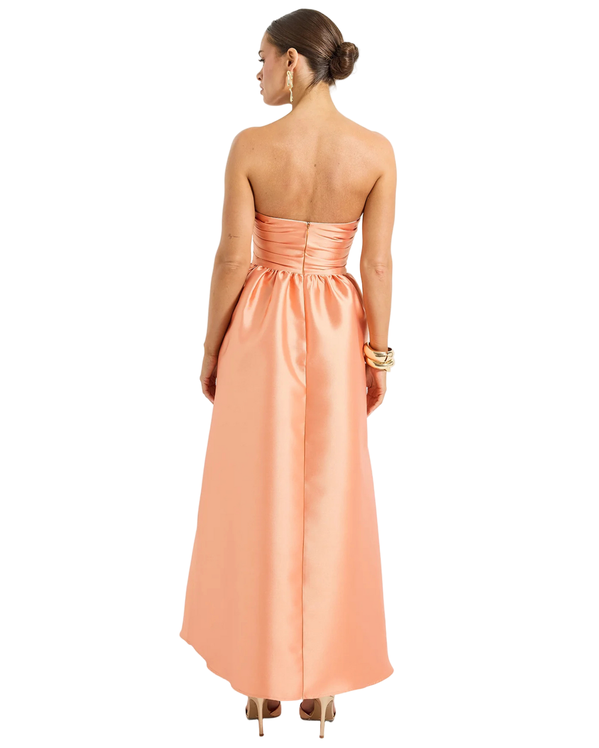 Woman wearing a peach strapless gown on a white background