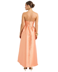 Woman wearing a peach strapless gown on a white background