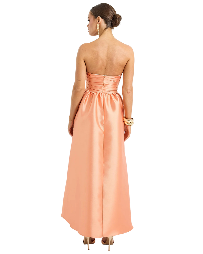 Woman wearing a peach strapless gown on a white background