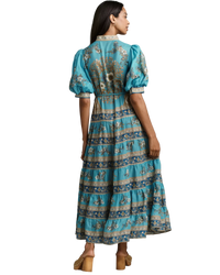 Woman wearing a blue floral dress against a neutral background