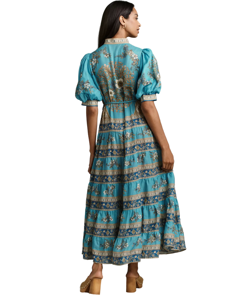 Woman wearing a blue floral dress against a neutral background