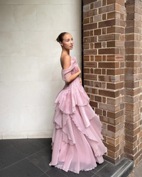 Aje Nisha Gown in fawn pink, lifestyle side view against a brick wall