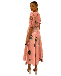 Woman wearing a pink dress with black patterns against a beige background