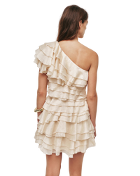 Woman wearing a one-shoulder ruffled dress against a plain background