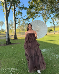 Aje Ophelia Lace Gown in chocolate brown, lifestyle view outdoors with a parasol, alternate pose