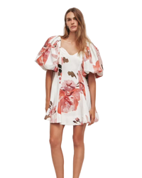 Woman wearing a floral dress with puffed sleeves against a plain background