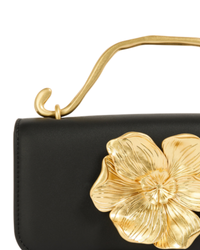 Aje Alessia Flower Clutch in black, close-up of the gold flower hardware