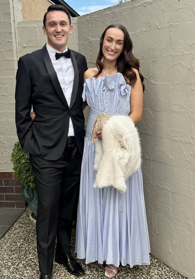 Woman wearing the Aje Aquiline Gown in French Blue beside a man in a tuxedo at a black tie event
