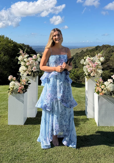 Woman wearing the Elliatt Armani Tiered Maxi Dress in Baby Blue Floral at an outdoor wedding ceremony