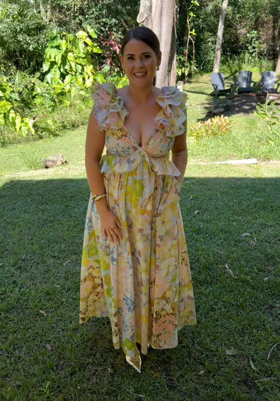 Woman wearing the Zimmermann Pop Ruffle Sleeve Maxi Dress in a garden